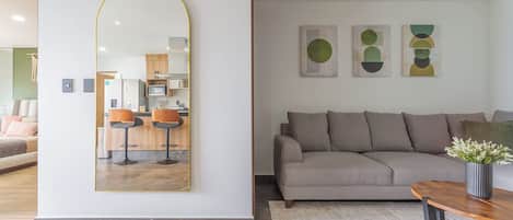A modern living room with a large mirror, a sofa, a coffee table, and abstract wall art.