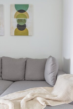Een grijze modulaire bank met een witte gebreide plaid.