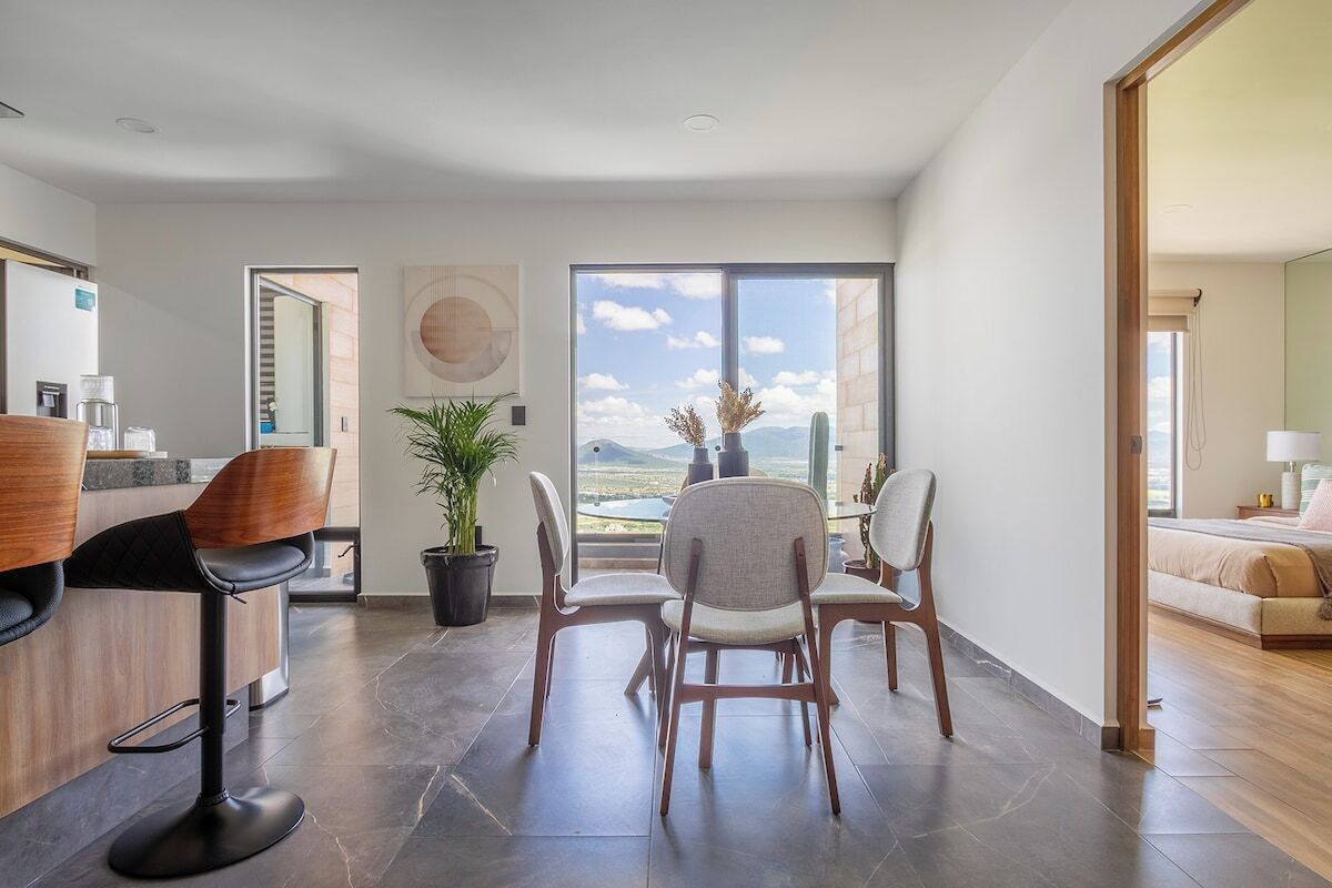 Interior moderno com área de refeições, bar e uma grande janela com vista para o exterior.