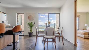 Interior moderno com área de refeições, bar e uma grande janela com vista para o exterior.