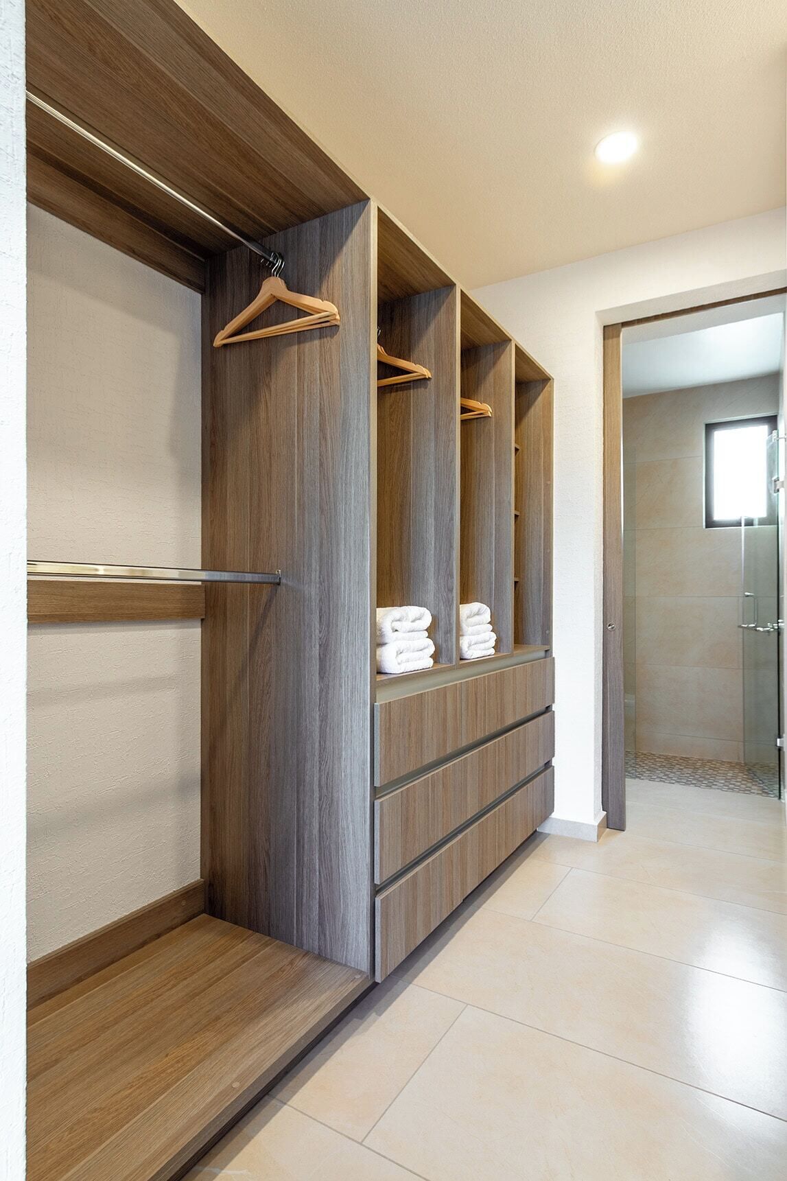 Un couloir avec une armoire en bois, un portant et un sol carrelé.