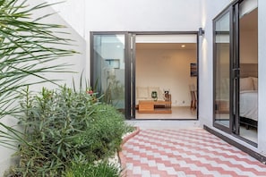 Habitación de hotel moderna con puerta de vidrio a un balcón, una zona de estar pequeña y una cama.