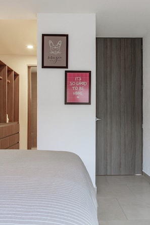 Un dormitorio con una cama, un armario y dos carteles motivacionales enmarcados en la pared.