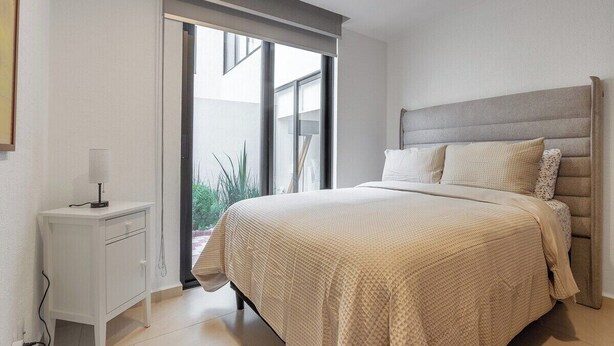 A bedroom with a bed, a bedside table, and a window. - Casa Lele by Cosmos Homes (Zakia)