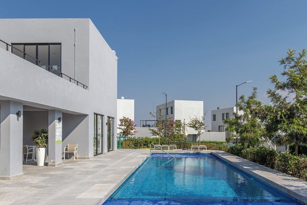 Un bâtiment moderne doté d’une piscine, d’un espace extérieur aménagé et offrant une vue sur un ciel dégagé.