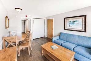 A room with a wooden dining table and chairs, a blue sofa, and a framed picture on the wall. - Amazing Oceanfront View  Condo with Pool & Hot tub (Myrtle Beach)