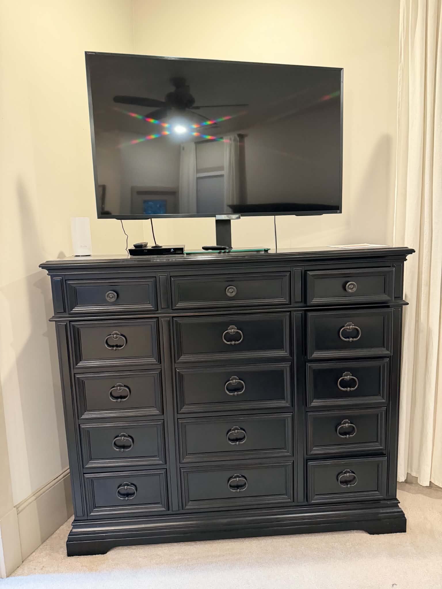 A black entertainment center with a flat-screen TV mounted above it.