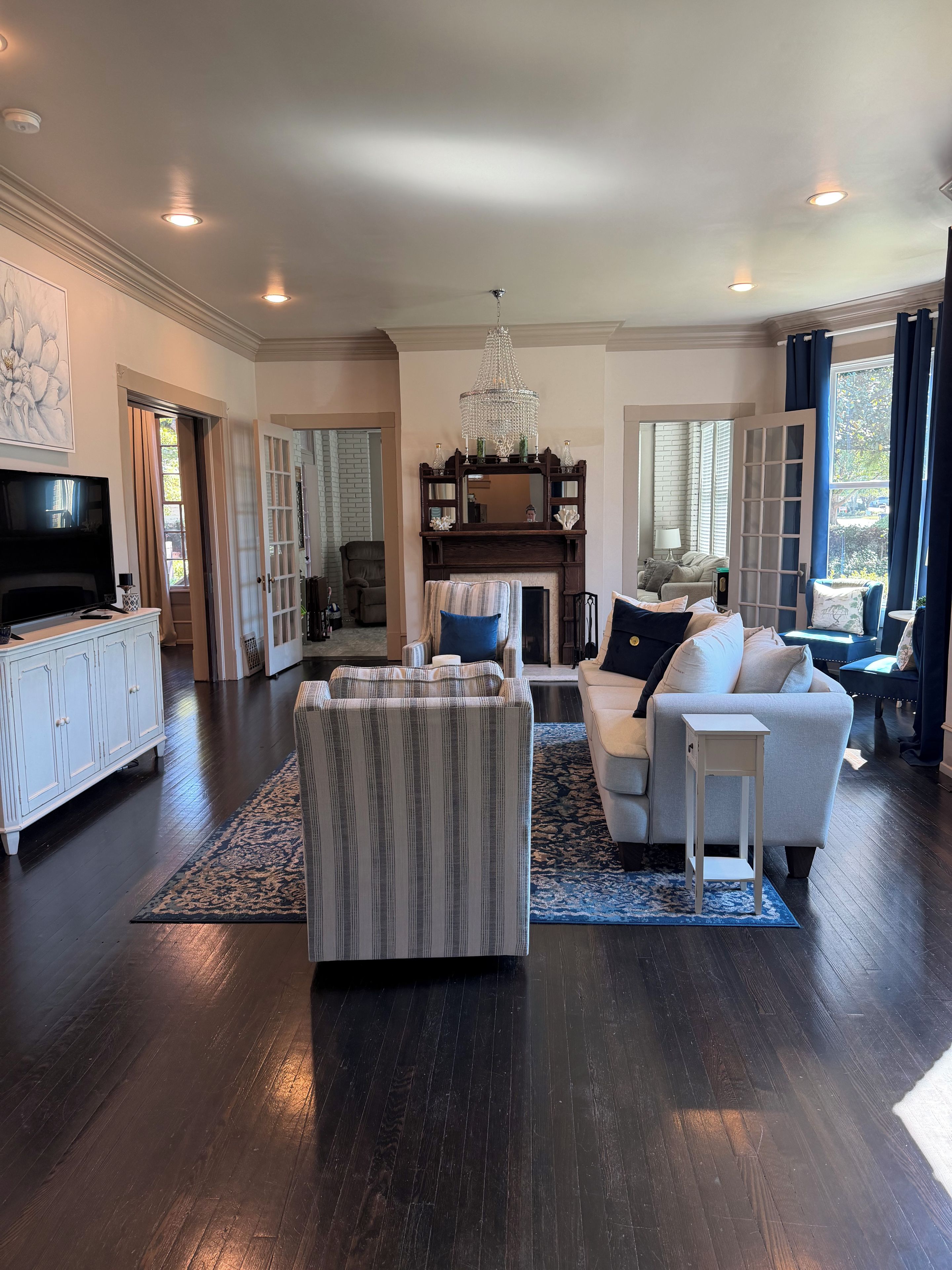 A spacious living room with a fireplace, a television, and a chandelier.