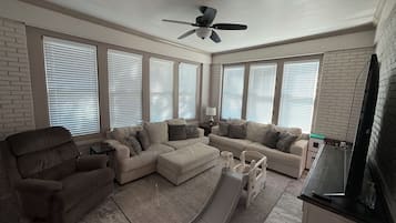 A living room with a sofa set, a small play area with a slide, and a ceiling fan.