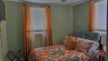 A bedroom with a bed, a ceiling fan, and a window with curtains.