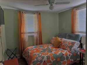 A bedroom with a bed, a ceiling fan, and a window with curtains.