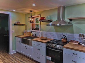 A modern kitchen with a stainless steel range hood, wooden countertops, and a built-in oven.