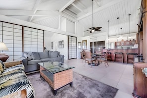 A spacious living area with a sofa, coffee table, and dining set. - Haleakala Shores | 4BR Total | Sleeps 12 (Kihei)