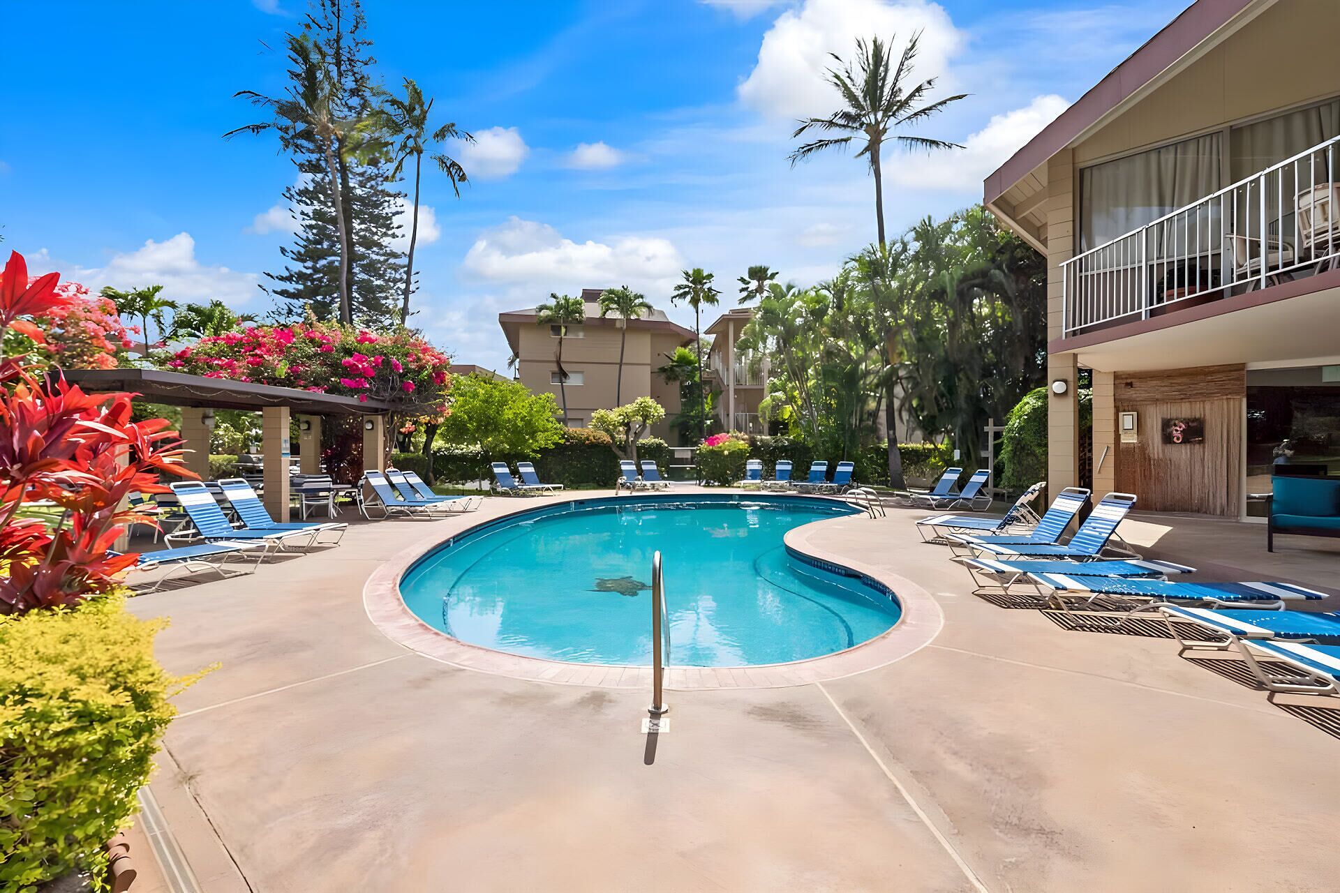 A pool area with lounge chairs and a clear blue pool.