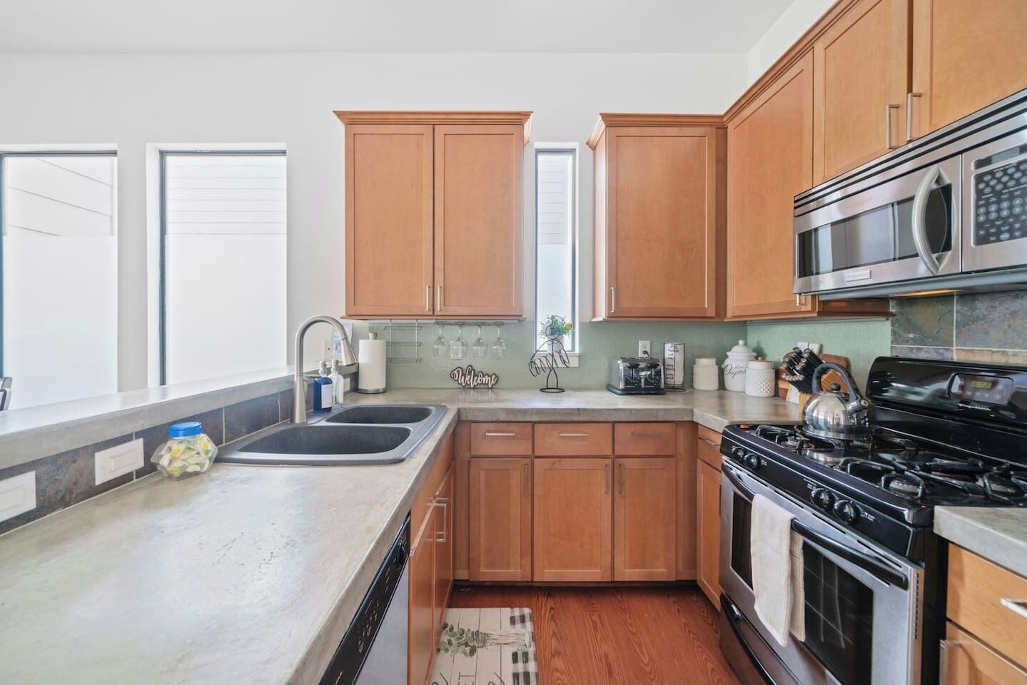 A kitchen with wooden cabinets, a stainless steel stove, a microwave, and a sink.