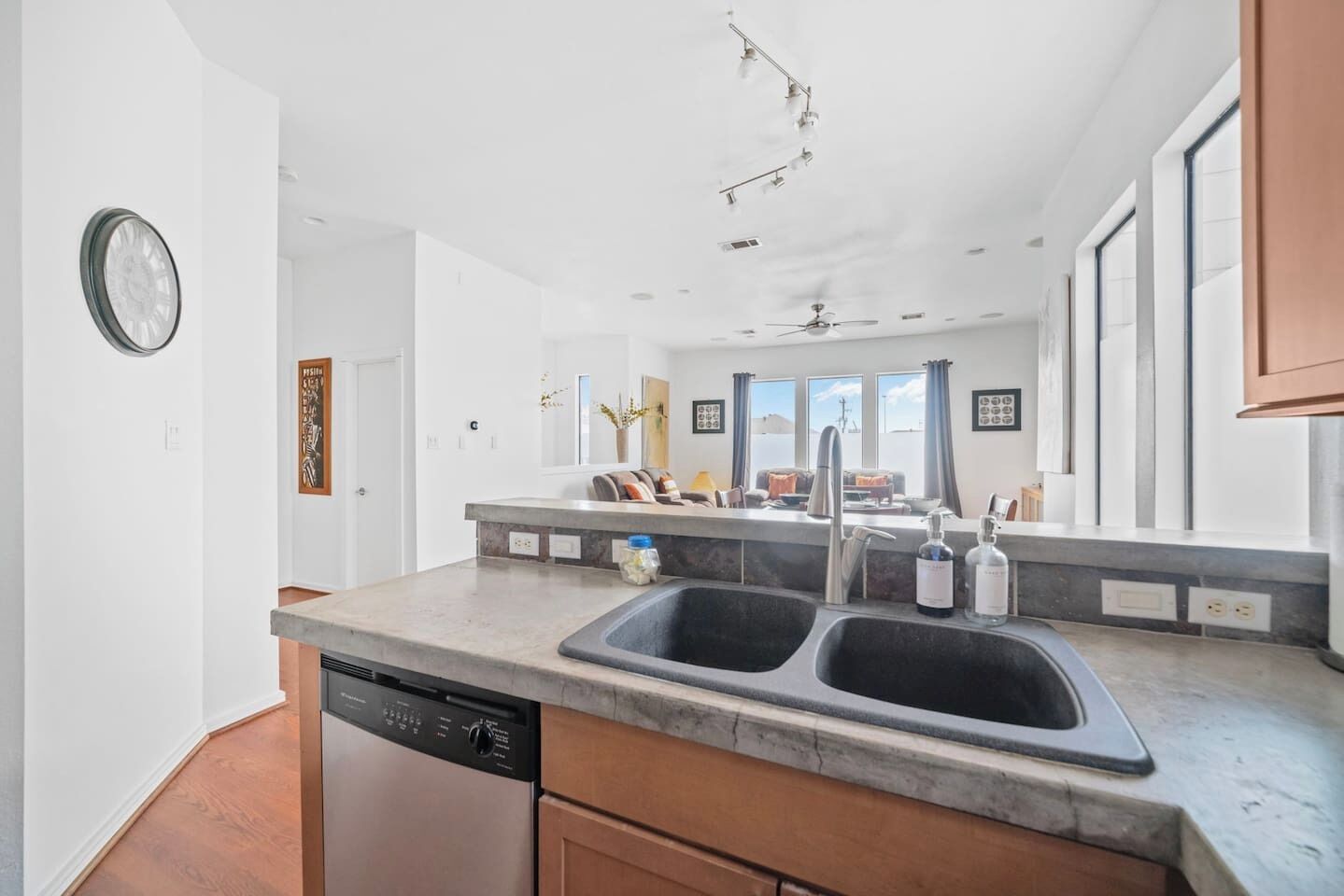 A modern kitchen with a dishwasher, double sink, and a large window.