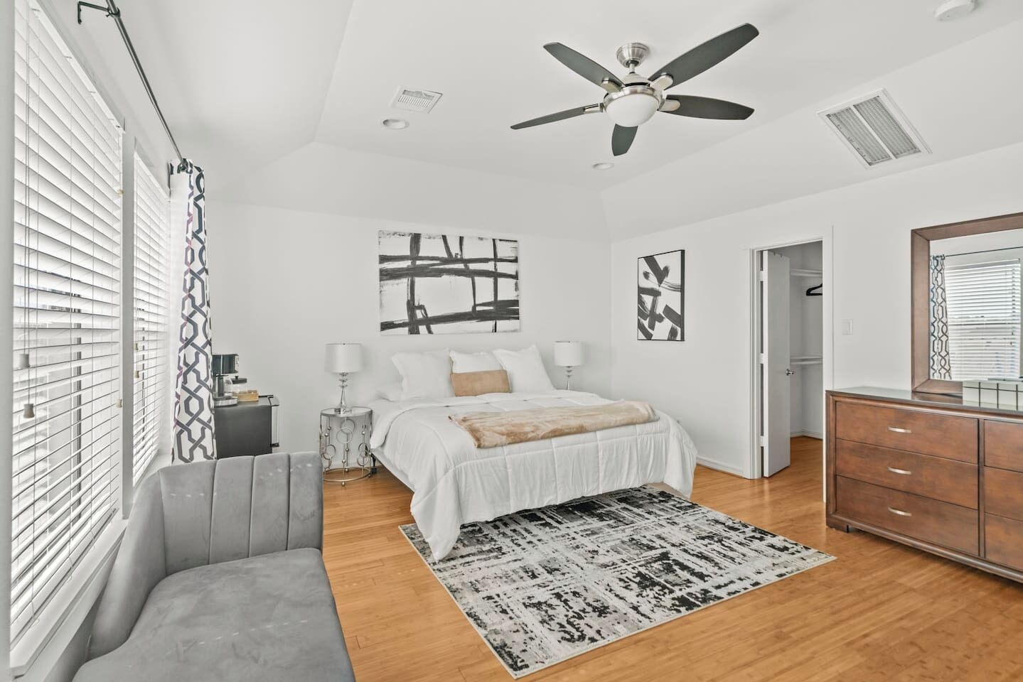A bedroom with a bed, bedside tables, a ceiling fan, and a window with blinds.