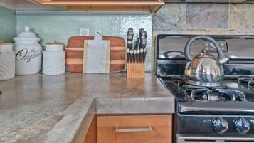A kitchen with wooden cabinets, a stainless steel stove, and a countertop with kitchen utensils.