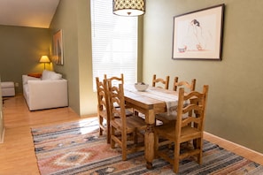 A dining area with a wooden table and chairs, a patterned rug, a sofa, and a lamp. - Charming Catalina Foothills Condo w/ Mountain Views, Gym, Pool and Spa (Tucson)