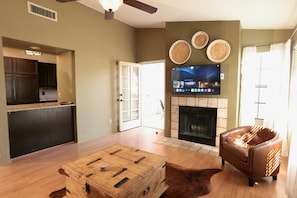 A living room with a fireplace, a television, and a leather couch. - Charming Catalina Foothills Condo w/ Mountain Views, Gym, Pool and Spa (Tucson)