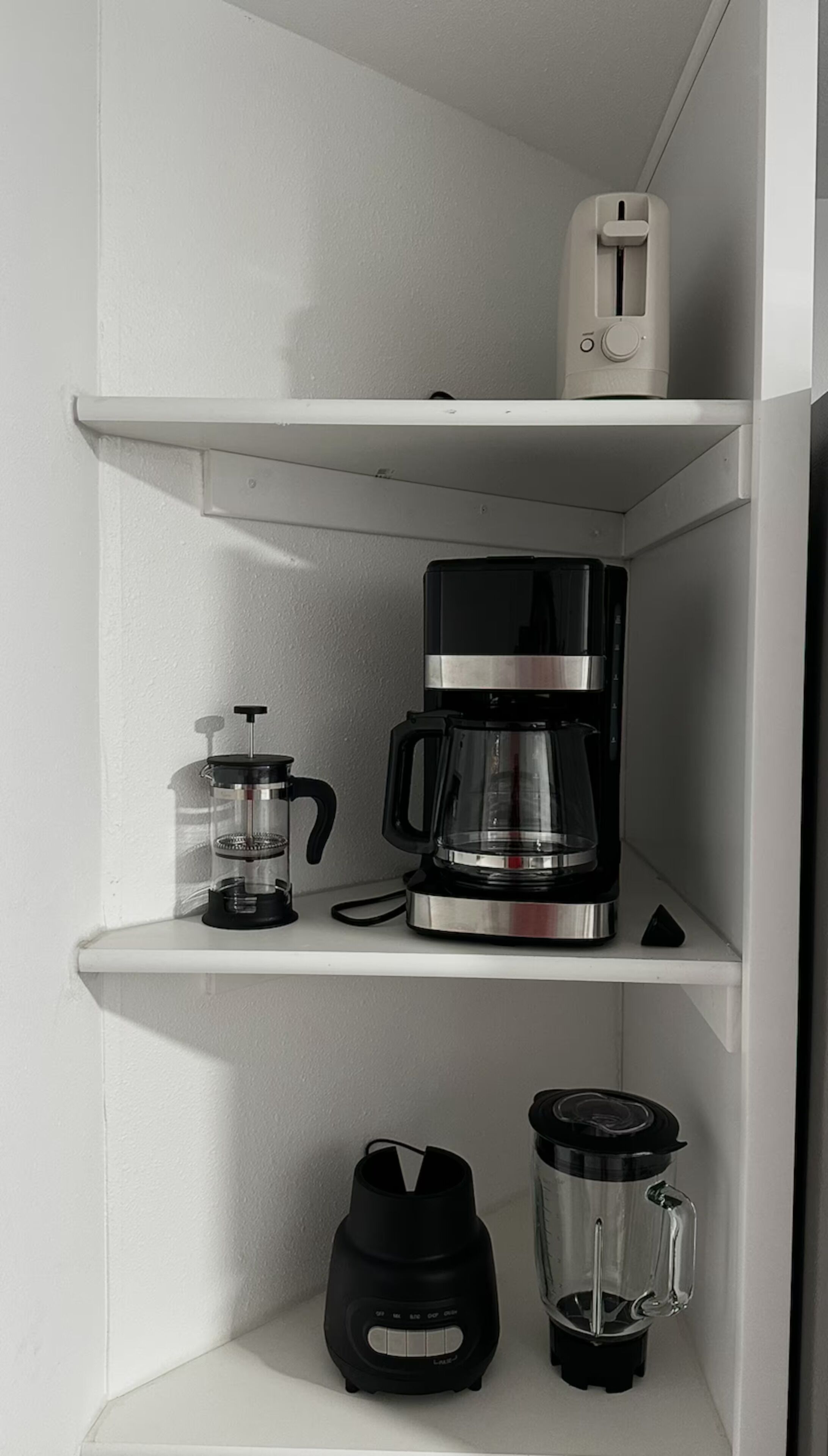 Une étagère de cuisine avec une machine à café, un mixeur et un thermos.