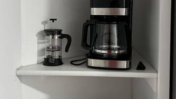 Une étagère de cuisine avec une machine à café, un mixeur et un thermos.