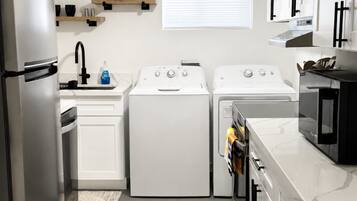 Une cuisine compacte équipée d’un réfrigérateur, d’un évier, d’un lave-linge, d’un sèche-linge, d’un four à micro-ondes et de placards.