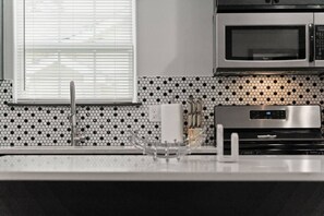 Eine Küche mit Mikrowelle, digitaler Uhr und Spüle mit modernem Wasserhahn.