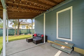 A covered porch with a sofa and a bench, a door, and a concrete floor. - Cozy 3-Bedroom Suburban Retreat near Downtown (Houston)