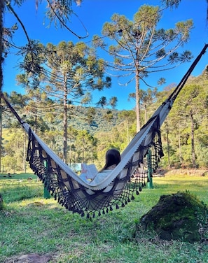 A hammock in a natural setting with trees in the background. - Frost Cabin • Urubici, SC | Private Stream, your retreat with a hot tub. (Urubici)