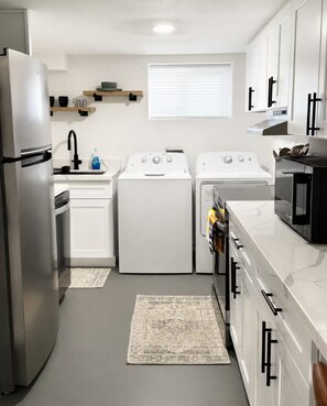 A compact kitchen with a refrigerator, stove, microwave, and washing machine. - The Little Harbor Retreat, Room Rental close to PSNS, Ferry, and more! (Bremerton)