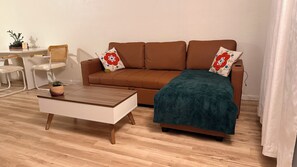 Un salon avec un canapé marron, une table basse en bois et un plaid bleu.