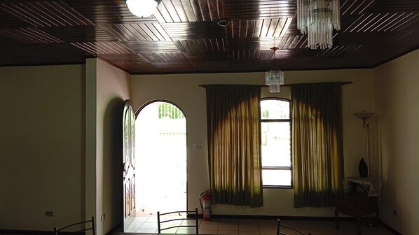 Una habitación con techo de madera, un amplio ventanal de arco y una mesa con sillas.
