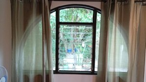 Ein Zimmer mit Fenster, Vorhängen und einem Ventilator.