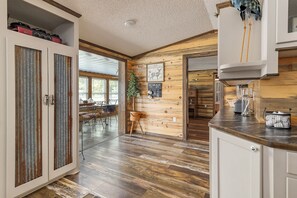 Une cuisine spacieuse avec des meubles de rangement en bois, un plan de travail et un coin repas comprenant un banc et des chaises.
