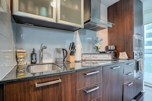 A modern kitchen with a stainless steel sink, wooden cabinets, and a coffee maker. - Luxury 3 bedrm 2 Baths Steps from CN Tower/Rogers Centers with One Parking Spot (Toronto)
