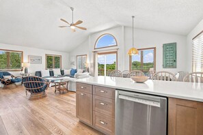 A spacious kitchen with a Bosch dishwasher, wooden cabinets, and a large island. - Salted Skyline | Private Community Beach Access | Hot Tub and Dog Friendly (Kitty Hawk)
