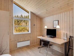 Een compacte kamer met een groot raam, een flatscreen televisie, een bureau en een stoel.