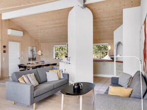 A modern interior with a grey sofa, a coffee table, and a dining area with a wooden table and chairs. - "Isbiorn" - 800m from the sea by Interhome (Løkken)