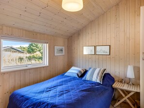 A bedroom with a large bed, a window with a view of greenery, and two framed pictures on the wall. - "Isbiorn" - 800m from the sea by Interhome (Løkken)