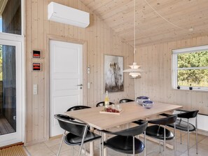 A dining area with a wooden table, black chairs, a pendant light, and a window with a view of trees. - "Isbiorn" - 800m from the sea by Interhome (Løkken)