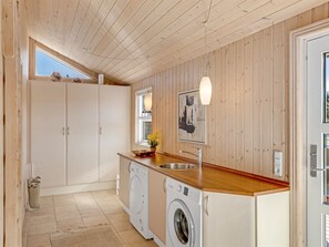 A compact kitchen with wooden cabinets, a washing machine, and a sink. - "Isbiorn" - 800m from the sea by Interhome (Løkken)