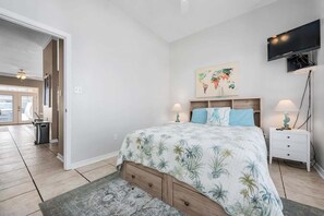 Ein Schlafzimmer mit einem Bett, einem Nachttisch, einem Fernseher und einer Weltkarte als Wandbild.