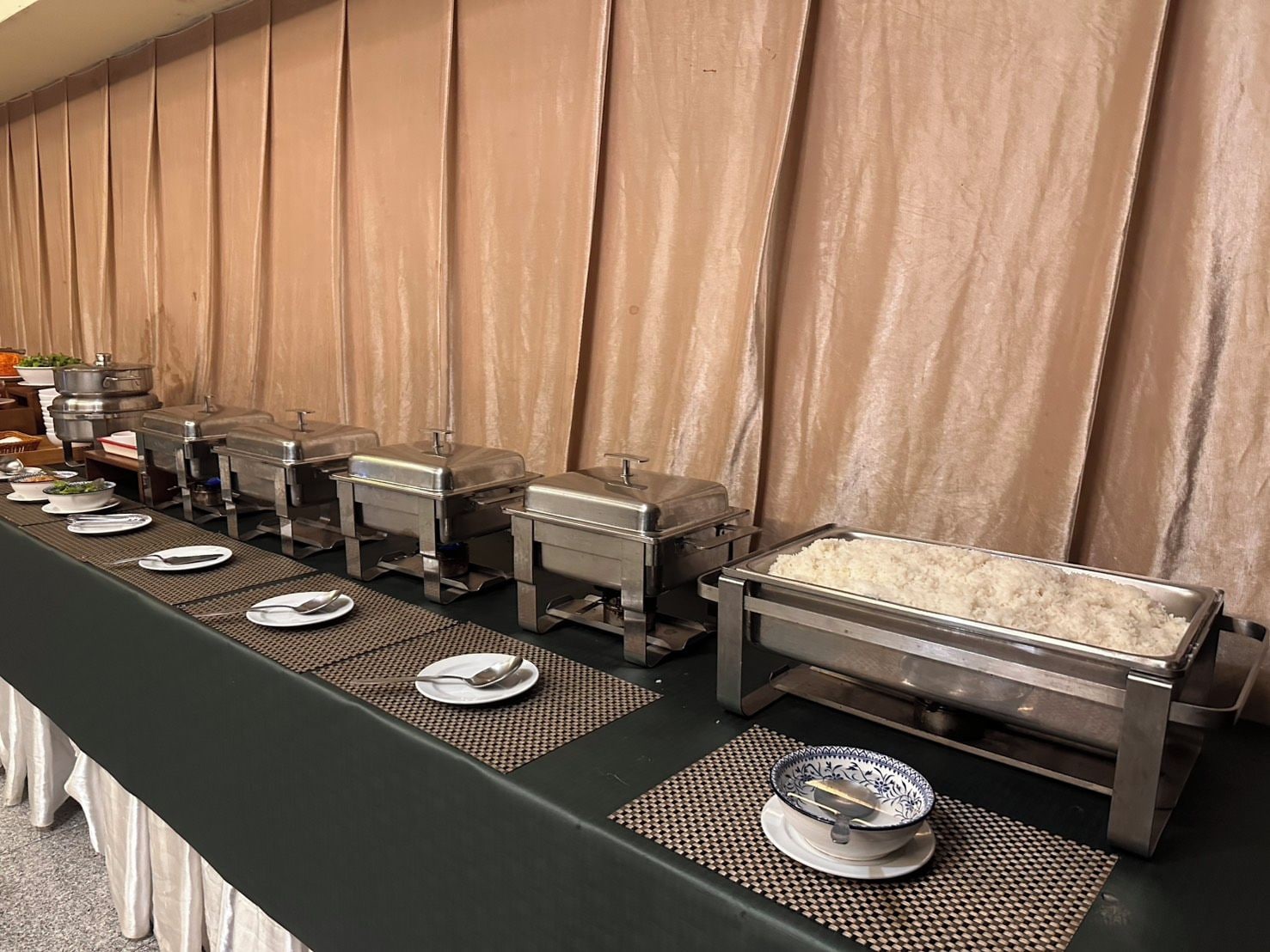 A buffet setup with multiple serving stations and a large container of rice.