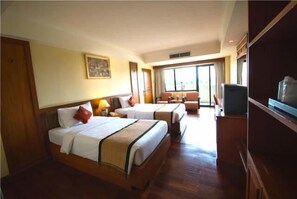 Habitación de hotel con dos camas, un televisor y un ventanal grande.