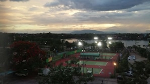 Vista de una cancha deportiva con focos, rodeada de árboles y una masa de agua.