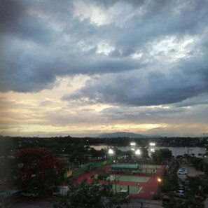 Vista de una cancha deportiva con focos, rodeada de árboles y una masa de agua.