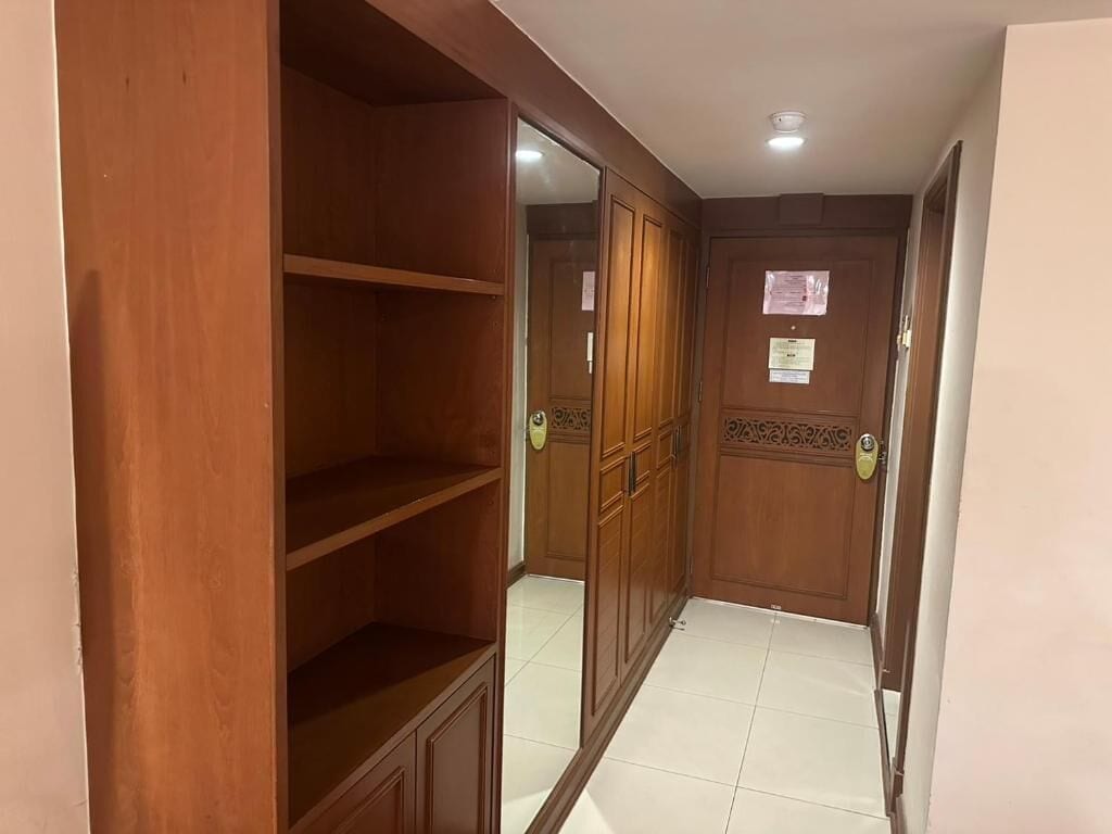 A corridor with wooden wardrobes and a tiled floor.