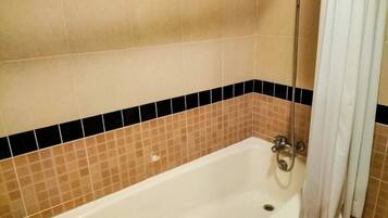 A bathroom with a bathtub, a shower, and a tiled wall.
