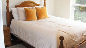 A bedroom with a wooden bed, white bedding, and a patterned rug. - Aryn Ridge House / 3BR / Near Casinos & Interstate (Lake Charles)